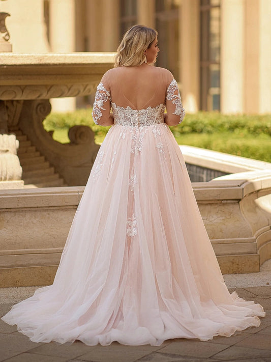 Blush pink plus size wedding dress with sheer illusion V-back, floral lace sleeves, embroidered waist and flowing tulle train