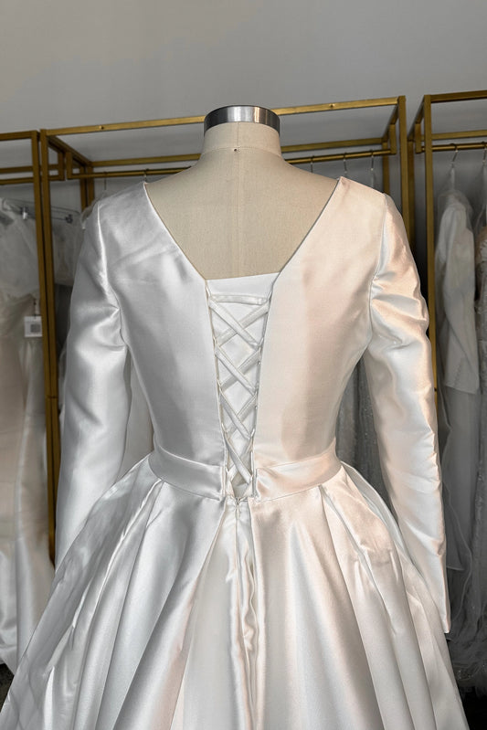 Ivory plus size long sleeve wedding dress with deep V-back, adjustable lace-up corset closure and full pleated satin-look ball gown skirt