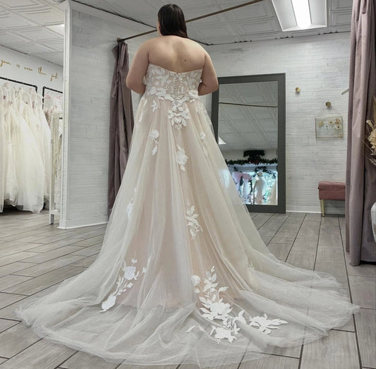 Ivory plus size wedding dress with sheer floral lace back, button-style detailing and flowing chapel-style tulle train