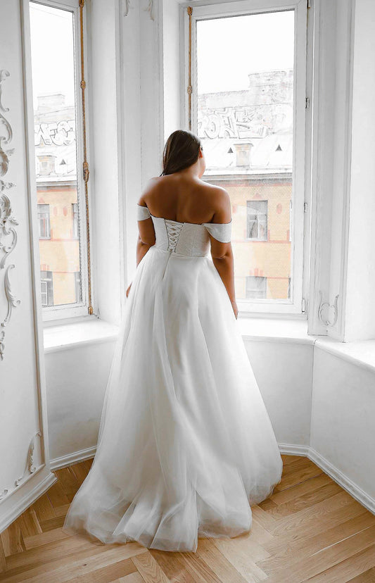 White plus size wedding dress with off-shoulder sleeves, sparkling lace-up corset back, crisscross ribbon closure and full tulle skirt