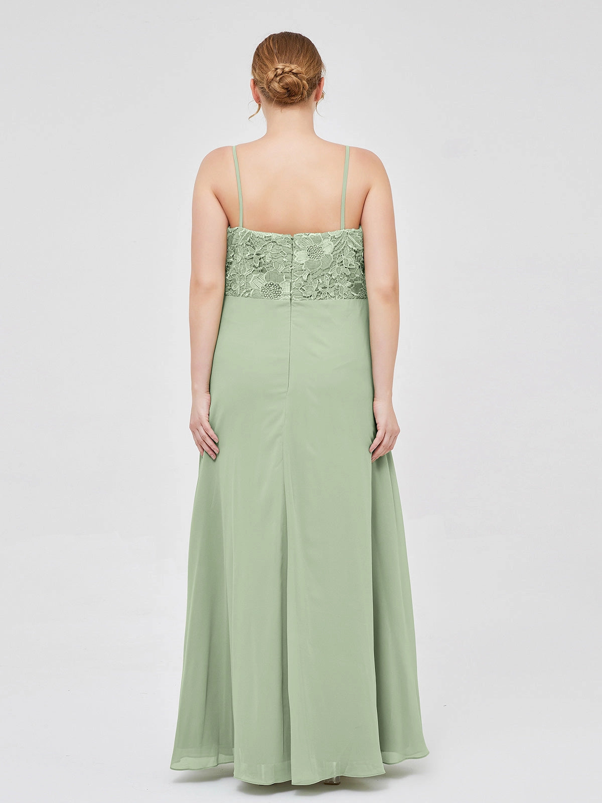 Back view of a Roselledress sage green bridesmaid dress with crossed straps, lace panels framing a triangular cutout and a gathered floor-length skirt.