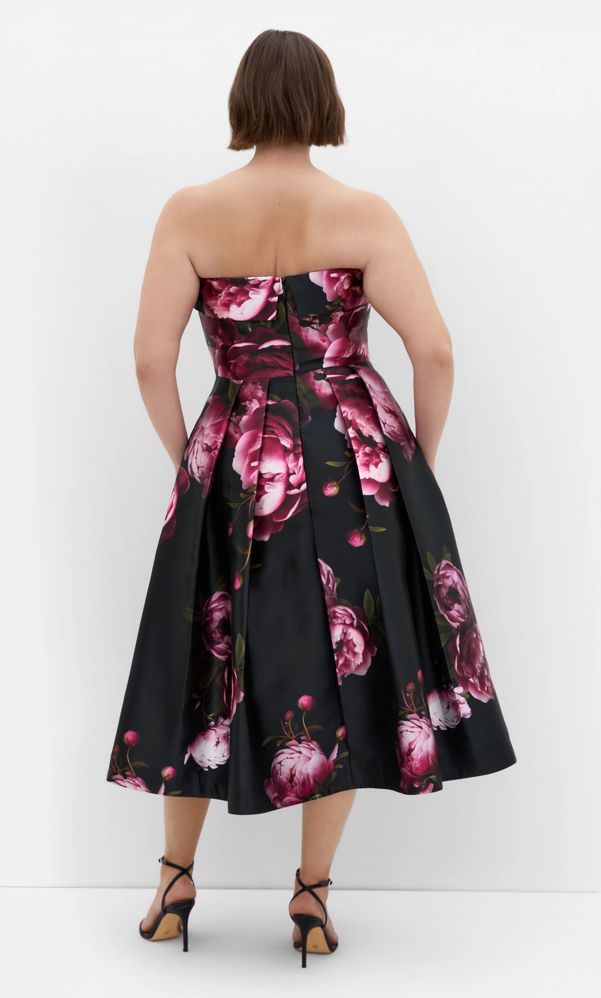 Black floral plus size midi dress back view, strapless neckline, center back zipper and pleated full A-line skirt
