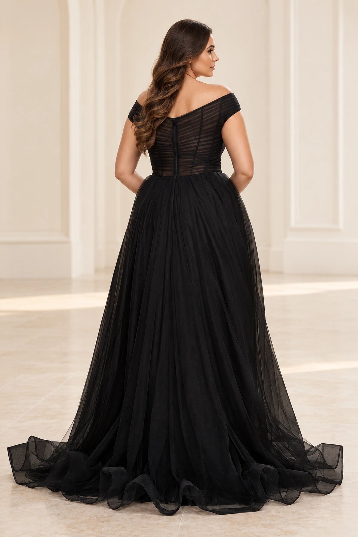 Back view of a black tulle prom dress with a sheer ruched bodice, vertical seam detailing, center zipper and sweeping train.