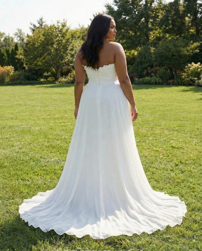 Back view of an ivory plus size strapless wedding dress with a scalloped neckline, center-back zipper and flowing train.