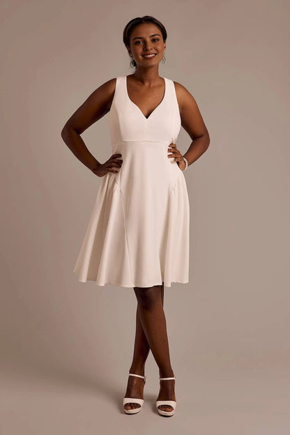 roselledress ivory matte crepe sleeveless deep v neck flowy pleated A-line mini bridesmaid dress neutral studio full body shot