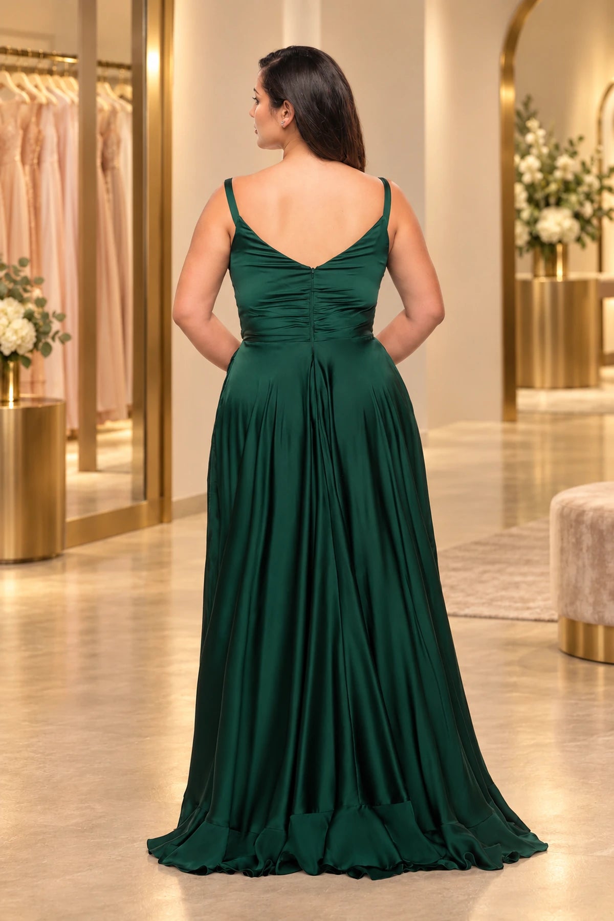 Back view of an emerald green satin prom dress with a V-back, center zipper, gathered bodice and flowing skirt with a ruffled sweep train.