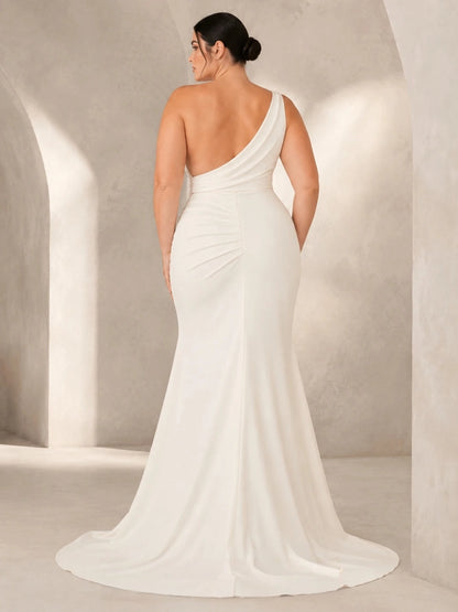 Back view of ivory plus size wedding dress featuring an asymmetric open back, diagonal shoulder strap and flowing train.