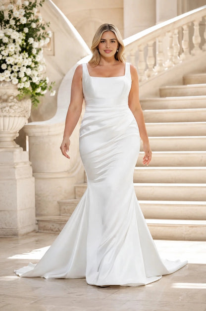 White plus size satin mermaid wedding dress with square neckline, wide straps, ruched waist and flowing train.