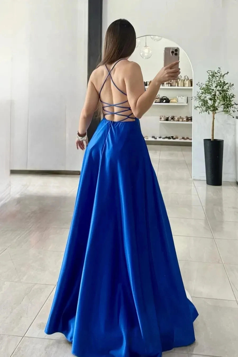 Back view of royal blue satin plus size prom dress with crisscross lace-up open back, spaghetti straps and flowing floor-length A-line skirt.