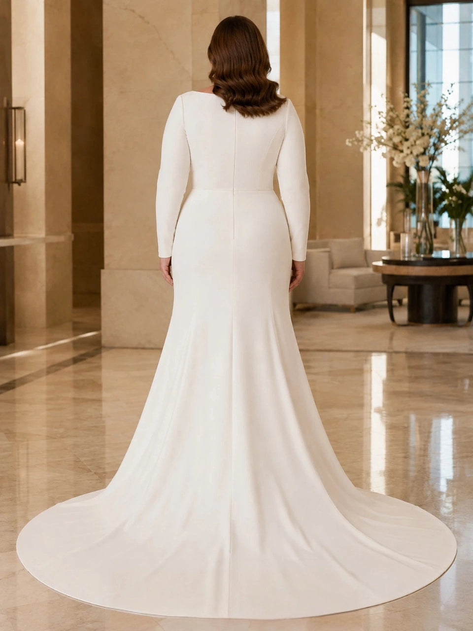Back view of an ivory plus size wedding dress featuring long sleeves, a closed back, center seam and flowing train.