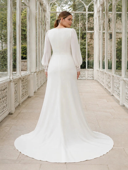 Back view of an ivory plus size wedding dress with long bishop sleeves, lace cuffs, a center zipper and chapel train.