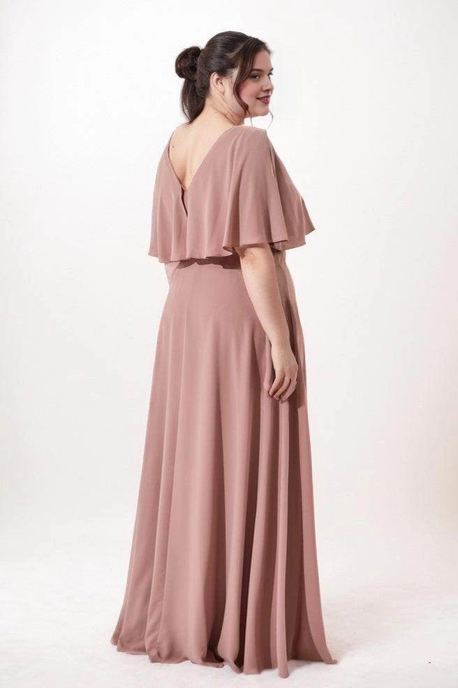 Dusty rose chiffon bridesmaid dress with a V-back, draped cape overlay and flowing floor-length A-line skirt, back view.