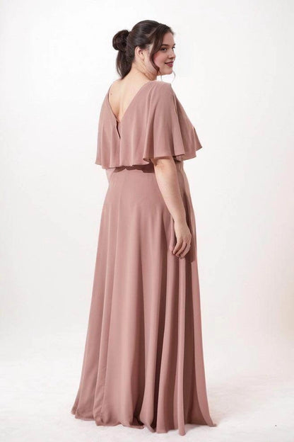 Dusty rose chiffon bridesmaid dress with a V-back, draped cape overlay and flowing floor-length A-line skirt, back view.