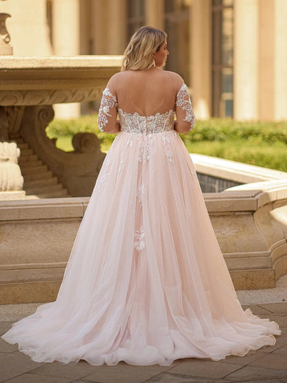 Blush pink plus size wedding dress with sheer illusion V-back, floral lace sleeves, embroidered waist and flowing tulle train