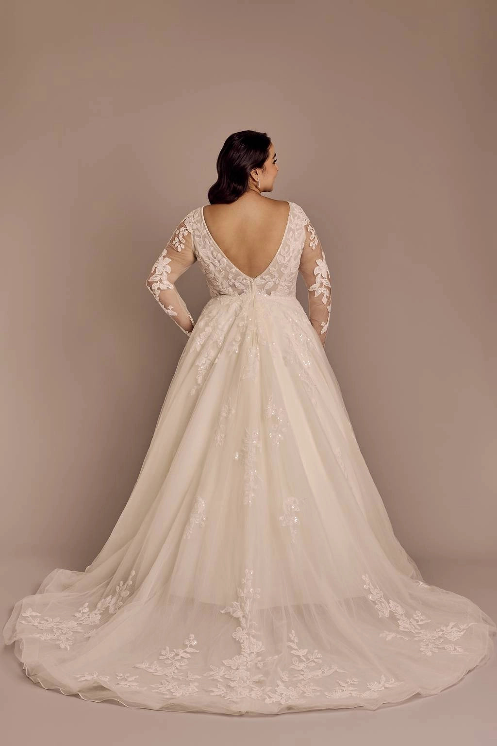 Champagne plus size lace wedding dress featuring deep V-back, sheer floral lace sleeves, fitted waist and flowing tulle skirt with long train
