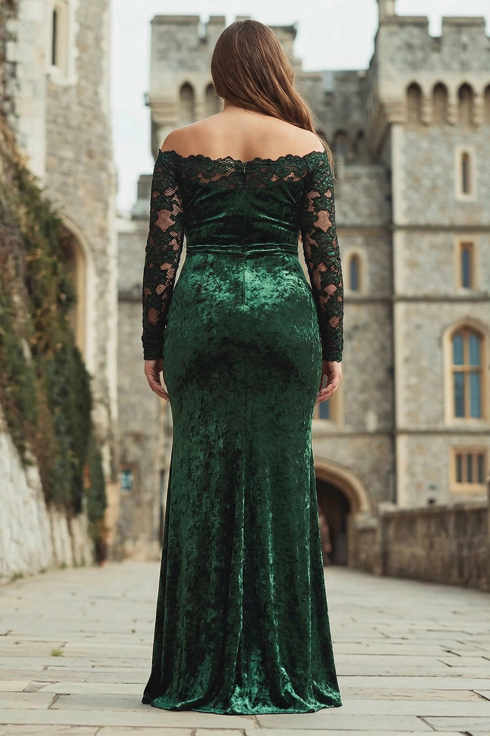 Back view of emerald green velvet plus size wedding guest dress featuring scalloped lace trim, long lace sleeves and a fitted mermaid silhouette.