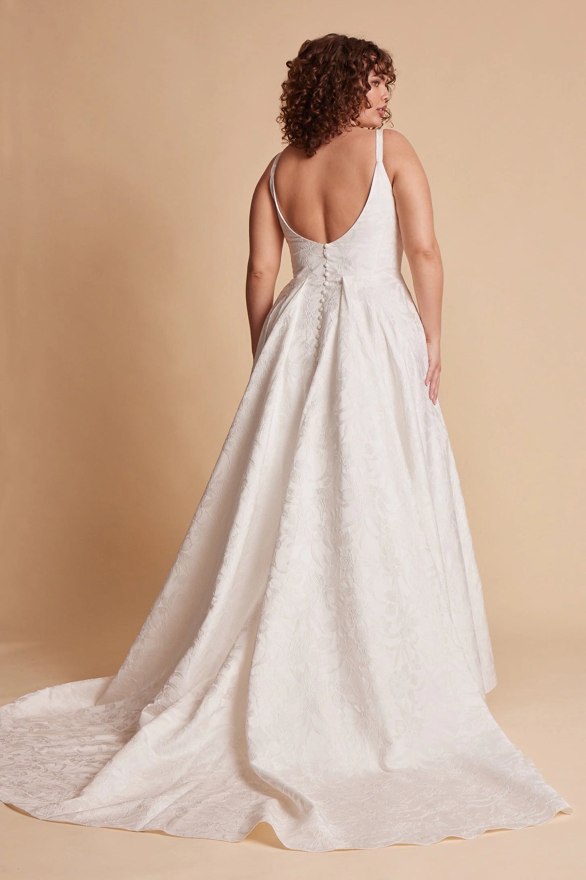 Ivory plus size floral wedding dress with low scoop back, covered button details, fitted waist and flowing A-line skirt with train