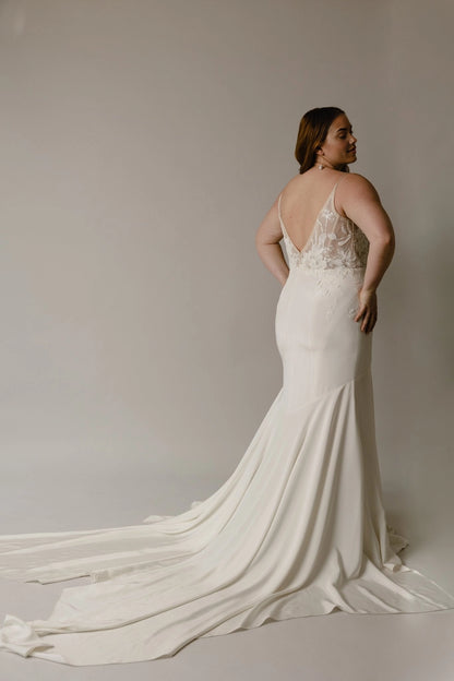 Ivory plus size mermaid bridal gown featuring deep V-back, sheer floral lace details, fitted hips and flowing long train