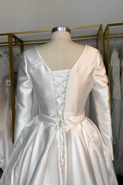 Ivory plus size long sleeve wedding dress with deep V-back, adjustable lace-up corset closure and full pleated satin-look ball gown skirt