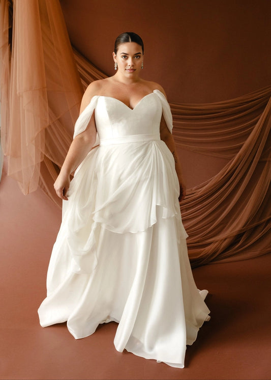 Ivory plus size A-line wedding dress with sweetheart neckline, draped off-shoulder sleeves, fitted waist and flowing layered skirt front view