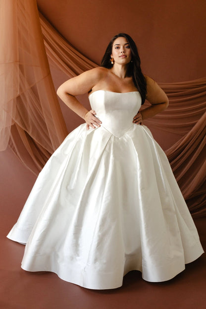 Ivory plus size ball gown wedding dress with strapless straight neckline, structured basque waist bodice and full satin skirt front view