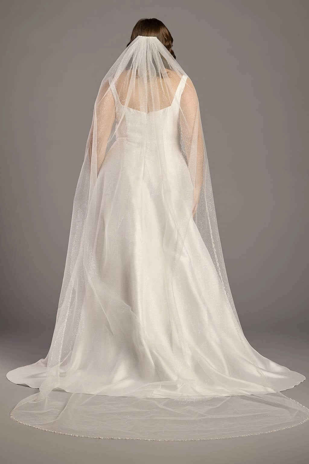Ivory plus size wedding dress with scoop back, wide shoulder straps, fitted waist and flowing A-line skirt shown beneath a sheer bridal veil