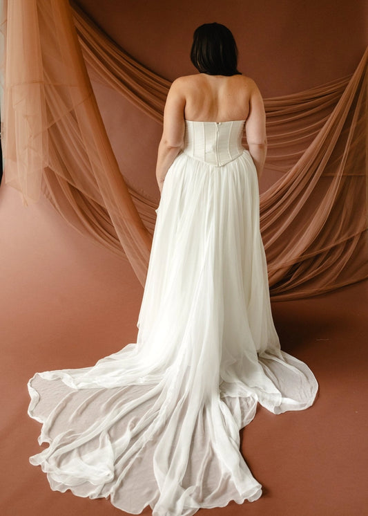Ivory plus size wedding dress with structured strapless bodice, center back zipper and flowing chiffon-look sweep train back view
