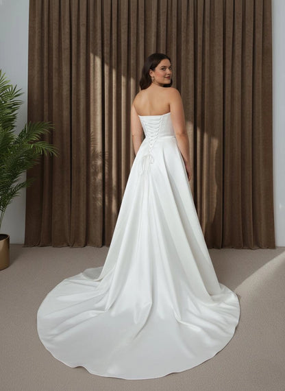Ivory plus size strapless wedding dress with lace-up corset back, crisscross ribbon closure and dramatic flowing overskirt with long train