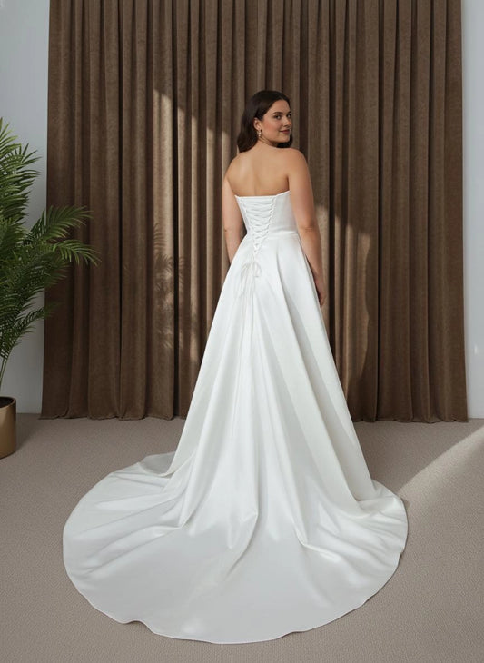 Ivory plus size strapless wedding dress with lace-up corset back, crisscross ribbon closure and dramatic flowing overskirt with long train