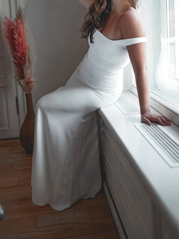 Side view of minimalist mermaid wedding dress featuring square neckline, elegant off shoulder design and floor length skirt.
