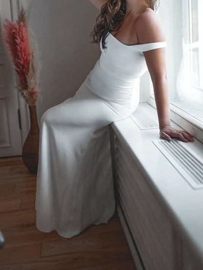 Side view of minimalist mermaid wedding dress featuring square neckline, elegant off shoulder design and floor length skirt.
