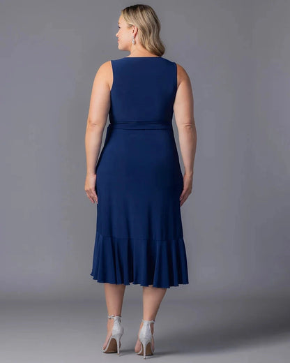 Back view of navy blue plus size wedding guest dress featuring a closed back, fitted waist and flowing ruffle midi hem by roselledress