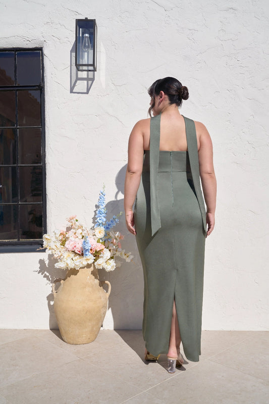 Back view of plus size sage green bridesmaid dress featuring straight strapless back, center zipper, long draped scarf panels and center back slit.