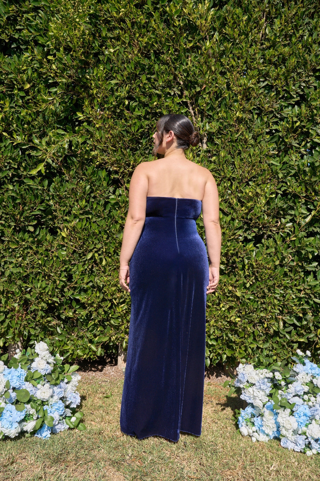 Back view of plus size navy blue velvet-look prom dress featuring a straight strapless back, fitted sheath silhouette and floor-length skirt by roselledress.