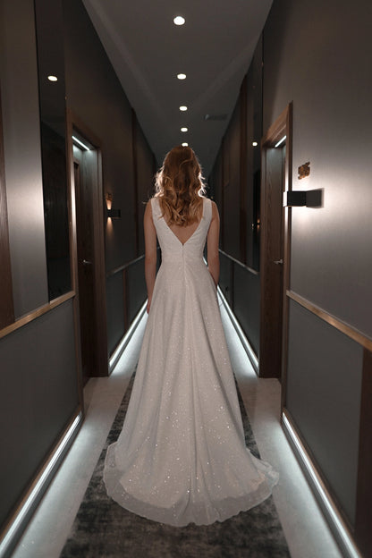 White plus size glitter wedding dress with deep V-back, center zipper closure, fitted waist and sparkling A-line skirt with sweep train