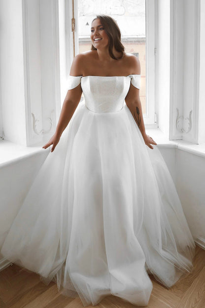 White plus size A-line wedding dress with shimmering straight neck bodice, off-shoulder sleeves and flowing layered tulle skirt